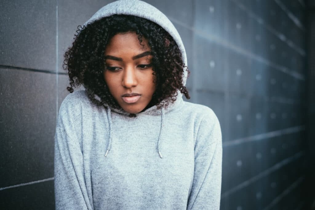 Teen girl in a hoodie looking sad and uncomfortable.