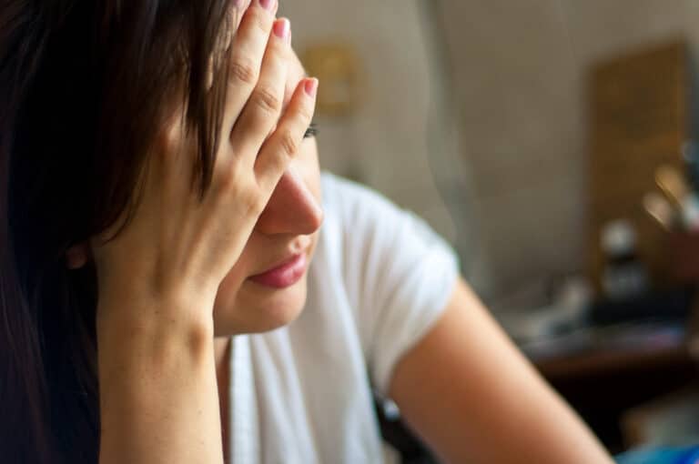 Woman with hand on her head looking stressed.